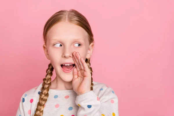 Foto von charmanten kniffligen Schulmädchen tragen Pullover Arm Mund erzählt Ihnen Geheimnis suchen leeren Raum isoliert rosa Farbe Hintergrund — Stockfoto