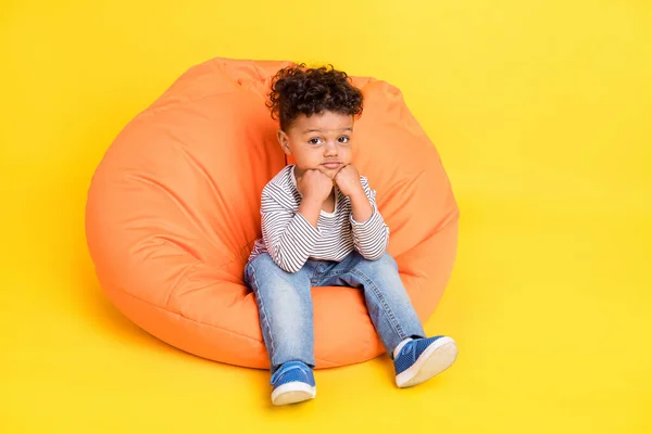 Фотографія повного розміру тіла маленького хлопчика, що сидить у сумці в повсякденному одязі ізольований яскраво-жовтий кольоровий фон — стокове фото