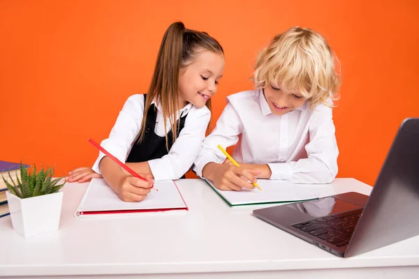 忙しい子供たちの写真を書く宿題デスクトップノートパソコンは、統一された隔離されたオレンジ色の背景を着用 — ストック写真