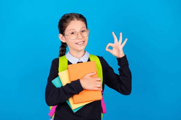 Foto di sorridere buon umore affascinante studentessa tenere libri mostrano ok segno gesto isolato su sfondo di colore blu — Foto Stock