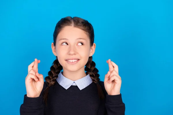 Φωτογραφία από χαρούμενα χαρούμενα θετικά μικρό κορίτσι ματιά κενό χώρο σταυρωμένα δάχτυλα επιθυμία απομονώνονται σε μπλε φόντο χρώμα — Φωτογραφία Αρχείου