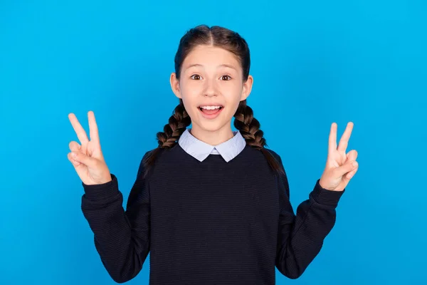 Foto av ung skola flicka glad positiv leende visa fred cool v-tecken isolerad över blå färg bakgrund — Stockfoto