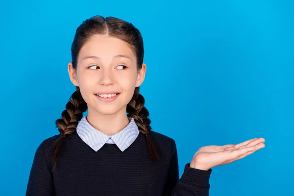 Foto van glimlachen charmante mooie schoolmeisje reclame product aanbevelen object geïsoleerd op blauwe kleur achtergrond — Stockfoto