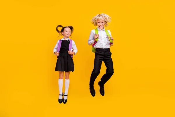 Fénykép őrült gondtalan gyerekek ugrás élvezni repülés viselet hátizsák iskola egyenruha elszigetelt sárga szín háttér — Stock Fotó