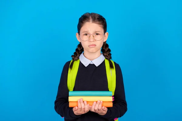 Stresli, olumsuz ruh hali olan okul kızının fotoğrafı. Sınav kitaplarını mavi arkaplan üzerine izole et. — Stok fotoğraf
