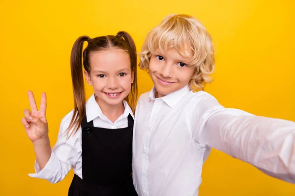 Фото веселих дружніх однокласників діти беруть селфі шоу v-знак одягу шкільної форми ізольований жовтий колір фону — стокове фото