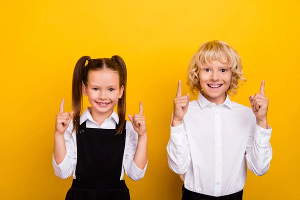 Photo de deux écoliers présentant vide espace vente porter uniforme scolaire isolé couleur jaune fond — Photo