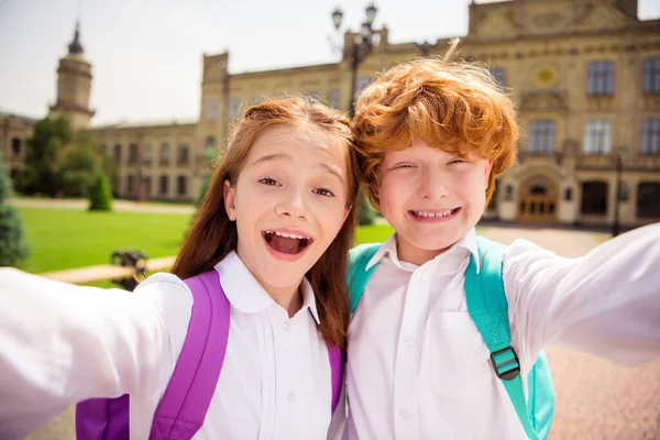 Foto de dois estudantes animados loucos fazer selfie ter quebrar divertido desgaste saco branco camisa uniforme parque fora — Fotografia de Stock
