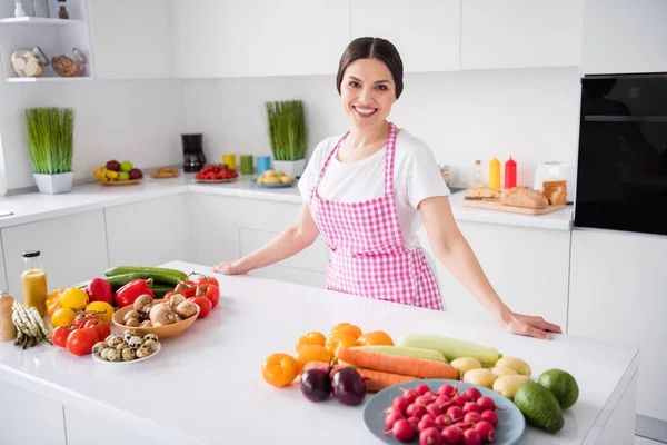 Φωτογραφία από αισιόδοξα καστανά μαλλιά νεαρή μαγείρισσα φορούν λευκό t-shirt ποδιά στην κουζίνα — Φωτογραφία Αρχείου