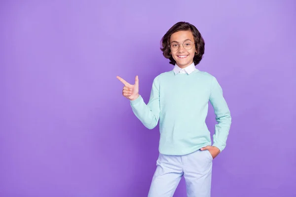 Photo of small funny brunet boy point empty space wear blue sweater spectacles isolated on purple background — Stock Photo, Image