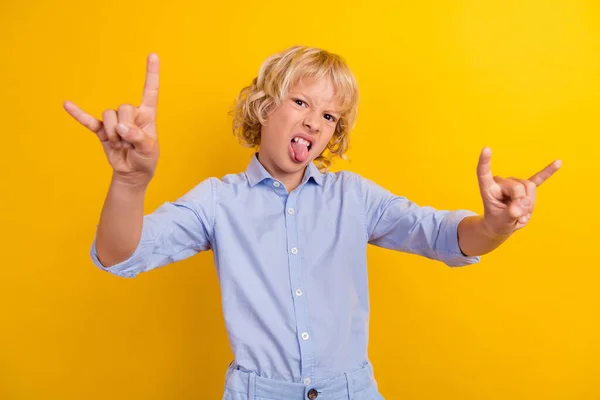 Photo de duper écolier grossier porter des bras chemise bleue montrant la langue de signe de roche dure isolé fond de couleur jaune — Photo