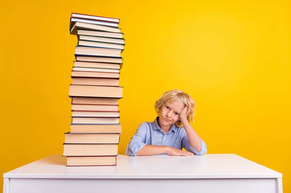 Foto de niño pequeño cansado con libros usan camisa azul aislada sobre fondo de color amarillo — Foto de Stock