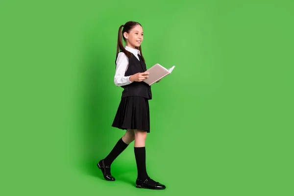 Comprimento total perfil de tamanho do corpo vista lateral do livro de leitura menina alegre atraente indo isolado sobre fundo de cor verde brilhante — Fotografia de Stock