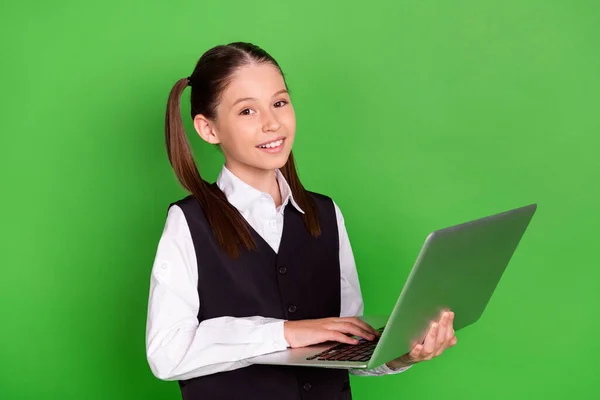 Fotografie z docela roztomilé školní dívka nosit černou bílou uniformu držení moderní zařízení s úsměvem izolované zelené pozadí — Stock fotografie