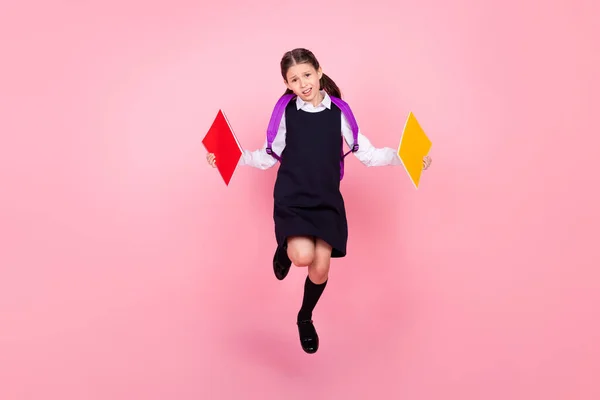 Pleine longueur taille du corps photo écolière sautant garder des livres malheureux avec devoirs isolé fond de couleur rose pastel — Photo