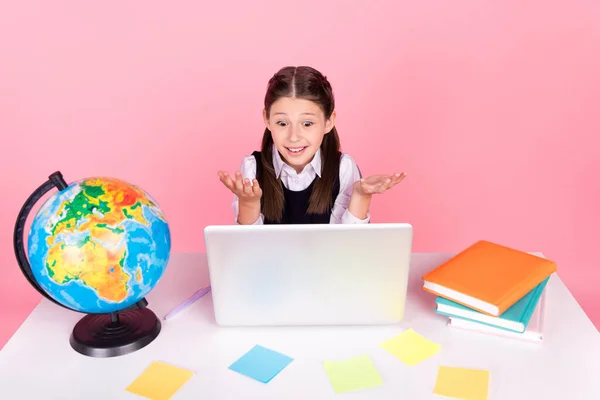 Foto retrato niña sentada en el escritorio usando la educación remota portátil no sé respuesta aislado pastel rosa color fondo — Foto de Stock