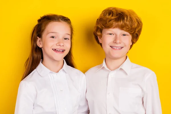 Portrait of two schoolchildren brother and sister go back to school hug embrace each other isolated on yellow color background — Stock Photo, Image