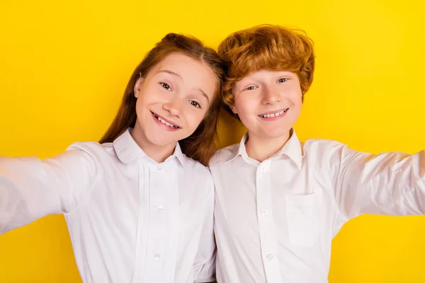 Фото юной улыбающейся веселой сестры брата вернуться в школу сделать селфи вместе изолированы на желтом фоне цвета — стоковое фото