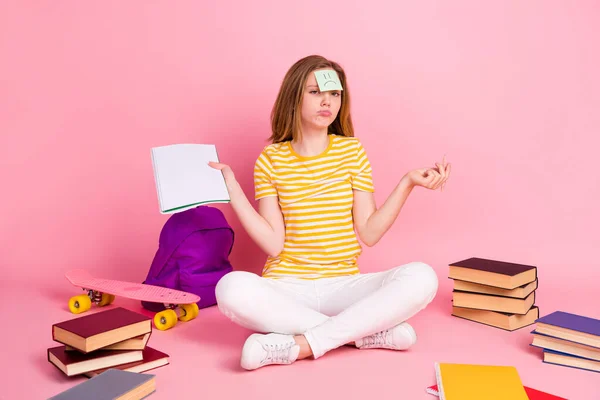 Bild av grinig flicka sitta golv sorgligt klistermärke panna skriva examen bära randig gul t-shirt isolerad rosa färg bakgrund — Stockfoto