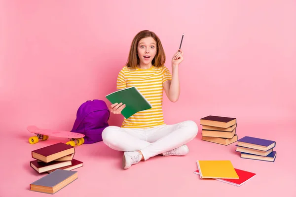Fotografie vzrušené génius dívka sedět podlaha psát domácí úkol mají nápad nosit pruhované žluté tričko izolované růžové barvy pozadí — Stock fotografie