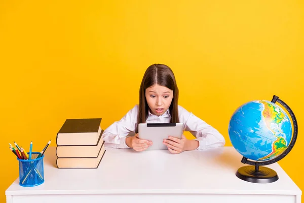 Foto Porträt Schulmädchen sitzt am Schreibtisch E-Book-Lektüre auf Unterricht schockiert isoliert lebendige gelbe Farbe Hintergrund — Stockfoto