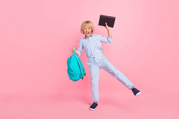 Photo de garçon d'école assez chanceux porter chemise bleue sac à dos souriant tenant livre marcher isolé fond de couleur rose — Photo