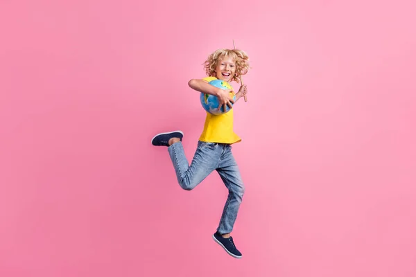 Повна фотографія профілю шкільного хлопчика щаслива позитивна посмішка стрибок тримайте глобус палицю ізольовано на фоні рожевого кольору — стокове фото