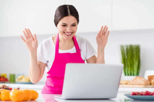 Φωτογραφία του εντυπωσίασε μελαχρινή μαλλιά χιλιετή κυρία συζήτηση φορητό υπολογιστή μάγειρας από το σπίτι φορούν λευκό t-shirt ποδιά στην κουζίνα — Φωτογραφία Αρχείου