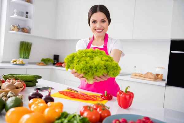 Фотопортретна жінка в фартусі посміхається, показуючи зелену капусту для салату — стокове фото