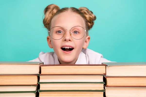 Photo of impressed little girl with books wear white shirt spectacles isolated on teal background — Stock Photo, Image