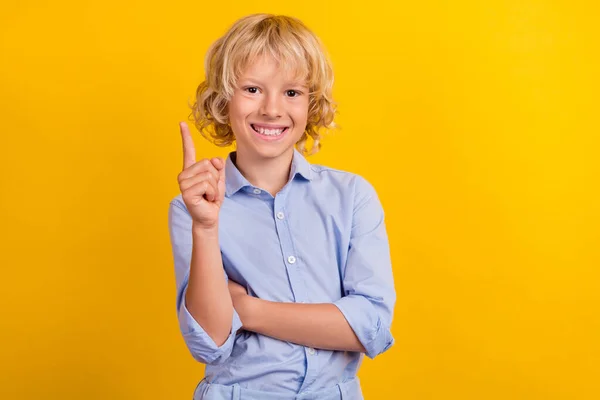 영리 한 남학생의 사진은 파란 셔츠를 입고 있고 웃으며 손가락으로 노란 배경을 표시하고 있다 — 스톡 사진