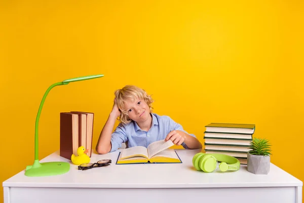 Foto de cansado molesto colegial usar camisa azul escritorio sentado después de haber leído muchos libro aislado color amarillo fondo — Foto de Stock