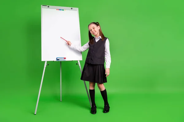 Foto van leuke grappige schoolmeisje gekleed wit zwart uniform glimlachen met les lege ruimte geïsoleerde groene kleur achtergrond — Stockfoto