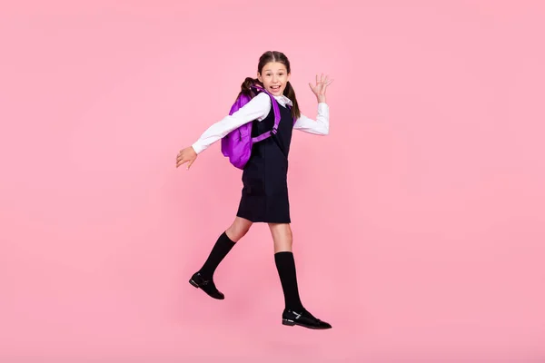 Perfil de corpo inteiro foto lateral da menina da escola feliz sorriso positivo acenando mão Olá salto isolado sobre cor rosa fundo — Fotografia de Stock