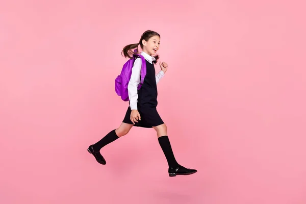 Full längd kropp storlek foto skolflicka hoppa hålla ryggsäck promenader till skolan isolerad pastell rosa färg bakgrund — Stockfoto
