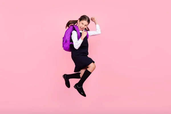 Foto lateral de perfil de tamaño completo de la niña de la escuela feliz saltador sonrisa positiva regocijarse victoria aislada sobre fondo de color rosa —  Fotos de Stock