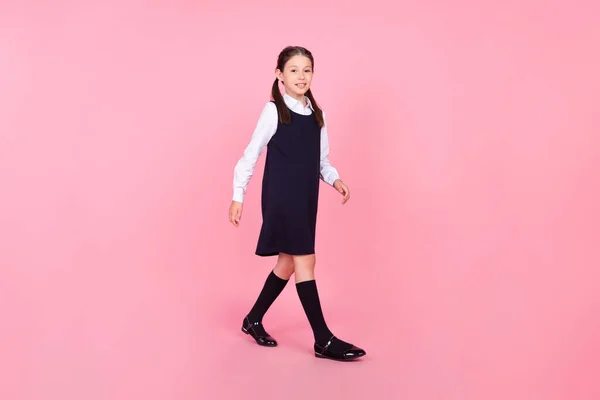 Πλήρες μήκος σώματος μέγεθος φωτογραφία μαθήτρια φορώντας στολή περπάτημα στο μάθημα απομονωμένο παστέλ ροζ χρώμα φόντο — Φωτογραφία Αρχείου