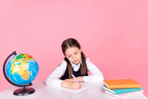 Foto van jong schoolmeisje zitten bureau klaslokaal schrijven notities les studie onderwijs geïsoleerd over roze kleur achtergrond — Stockfoto