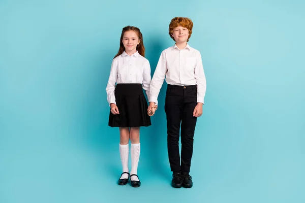 Foto de dois estudantes amigáveis positivos de mãos dadas usar camisa branca uniforme isolado fundo de cor azul — Fotografia de Stock