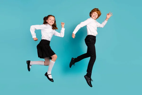 Vista completa del tamaño del cuerpo de dos niños alegres saltando caminando buen humor aislado sobre fondo de color azul brillante — Foto de Stock