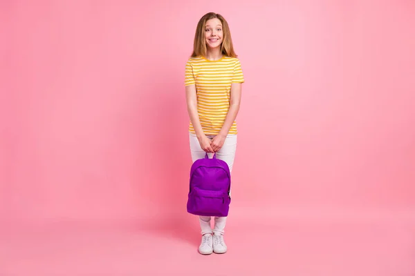 Foto von entzückenden fröhlichen positiven Mädchen zahmes Lächeln tragen Rucksack gestreiften gelben T-Shirt isoliert rosa Hintergrund — Stockfoto