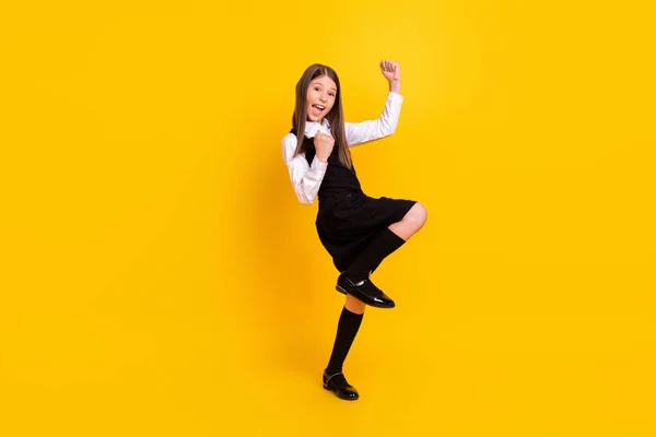 Full längd kropp storlek foto skolflicka i uniform gest som vinnare isolerad ljus gul färg bakgrund — Stockfoto