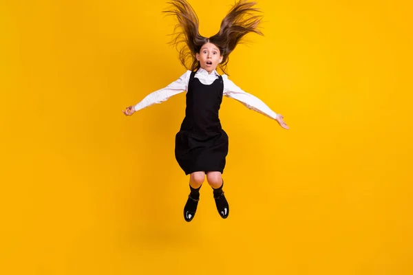 Foto de comprimento total de surpreendido chocado menina louca saltar para cima voar cabelo de volta para a escola isolado no fundo de cor amarela — Fotografia de Stock