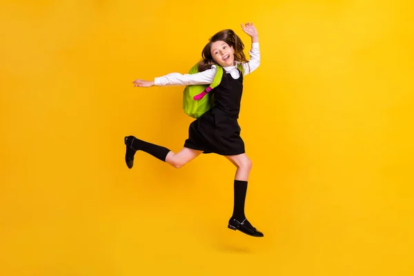 Foto de larga duración de alegre niña feliz sorprendida saltar hasta llevar mochila aislada en el fondo de color amarillo —  Fotos de Stock