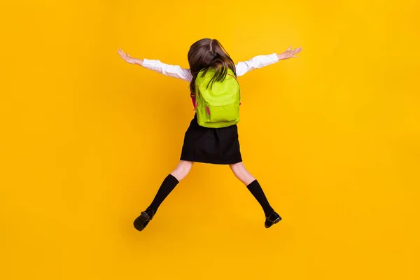 Zadní strana páteře pohled fotografie malé školačky skok nahoru nosit batohy solated na žluté barvy pozadí — Stock fotografie