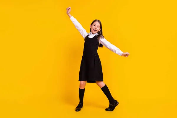 Longitud completa tamaño del cuerpo foto colegiala gesto como ganador sonriendo en uniforme aislado color amarillo brillante fondo —  Fotos de Stock