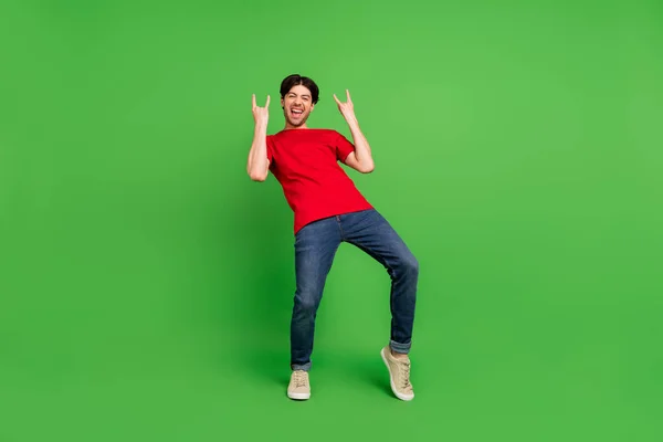 Photo de rocker drôle fan guy profiter concert montrer deux cornes geste porter rouge t-shirt isolé fond de couleur verte — Photo