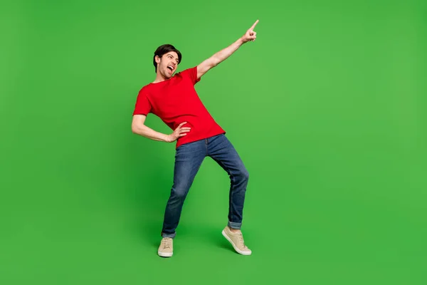 Foto von aufgeregten verrückten Kerl Tanz direkte Finger leeren Raum tragen rotes T-Shirt isoliert grüne Farbe Hintergrund — Stockfoto