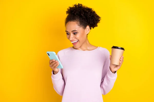 Foto de espantado chocado pele escura mulher feliz segurar telefone sorriso café isolado no fundo de cor amarela — Fotografia de Stock