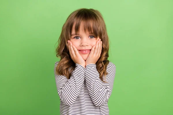 Foto de fresco pouco loiro cabelo menina mãos bochechas usar camisa listrada isolado na cor verde backgound — Fotografia de Stock